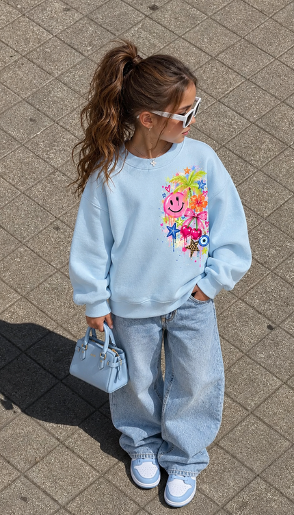 Front of the Sunshine & Smiles kids' sweatshirt in baby blue with a bright cluster of a pink smiley face, palm tree, flowers and stars on the chest – Miss Runway