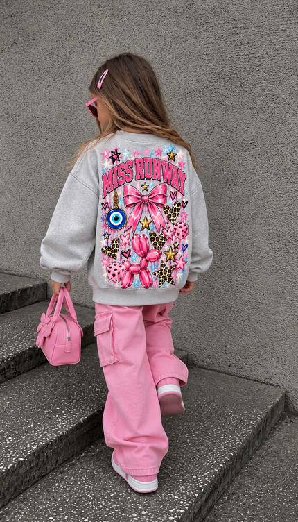 Back of the Bubblegum Dreams kids' sweatshirt in grey marl with pink MISS RUNWAY lettering with a large pink bow, an evil eye, leopard hearts, a balloon dog and stars – Miss Runway