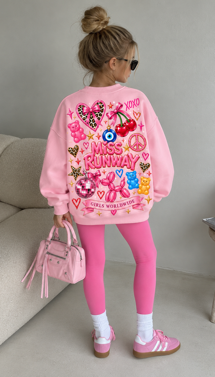 Back of the Girls Worldwide kids' sweatshirt in pink with pink MISS RUNWAY lettering with a leopard heart, cherries, an evil eye, a peace sign, gummy bears, a balloon dog, a disco ball and a Girls Worldwide banner – Miss Runway
