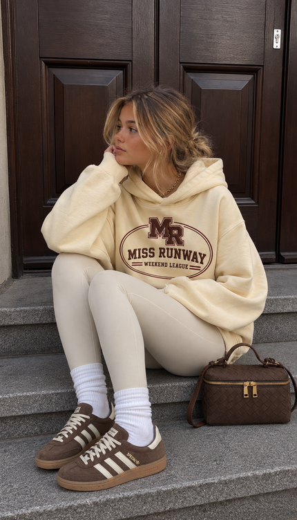 Front of the Weekend League hoodie in cream with a burgundy MR monogram above arched MISS RUNWAY lettering and a Weekend League badge – Miss Runway