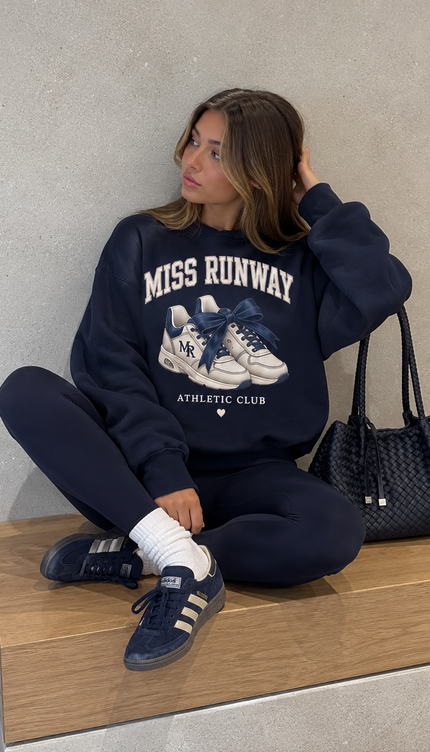 Front of the Miss Runway Athletic Club kids' sweatshirt in navy with cream MISS RUNWAY lettering above a pair of trainers with navy laces and Athletic Club – Miss Runway