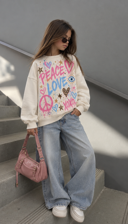 Girl wearing the Pastel Peace Love Sweatshirt in cream with a pastel peace and love print by Miss Runway