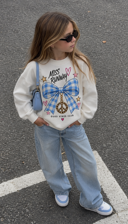 Girl wearing the Gingham Bow Good Vibes Sweatshirt in cream with a blue gingham bow print by Miss Runway