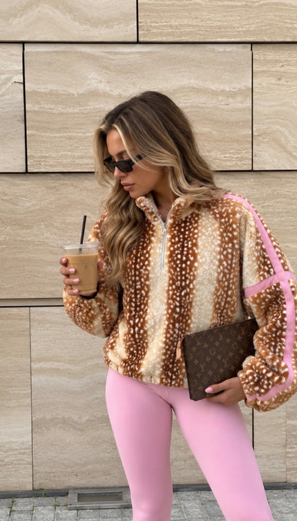 Woman wearing the Deer Print Lightweight Zip-Neck Fleece Pink, a half-zip fleece in caramel and cream deer print with pink sleeve stripes, by Miss Runway